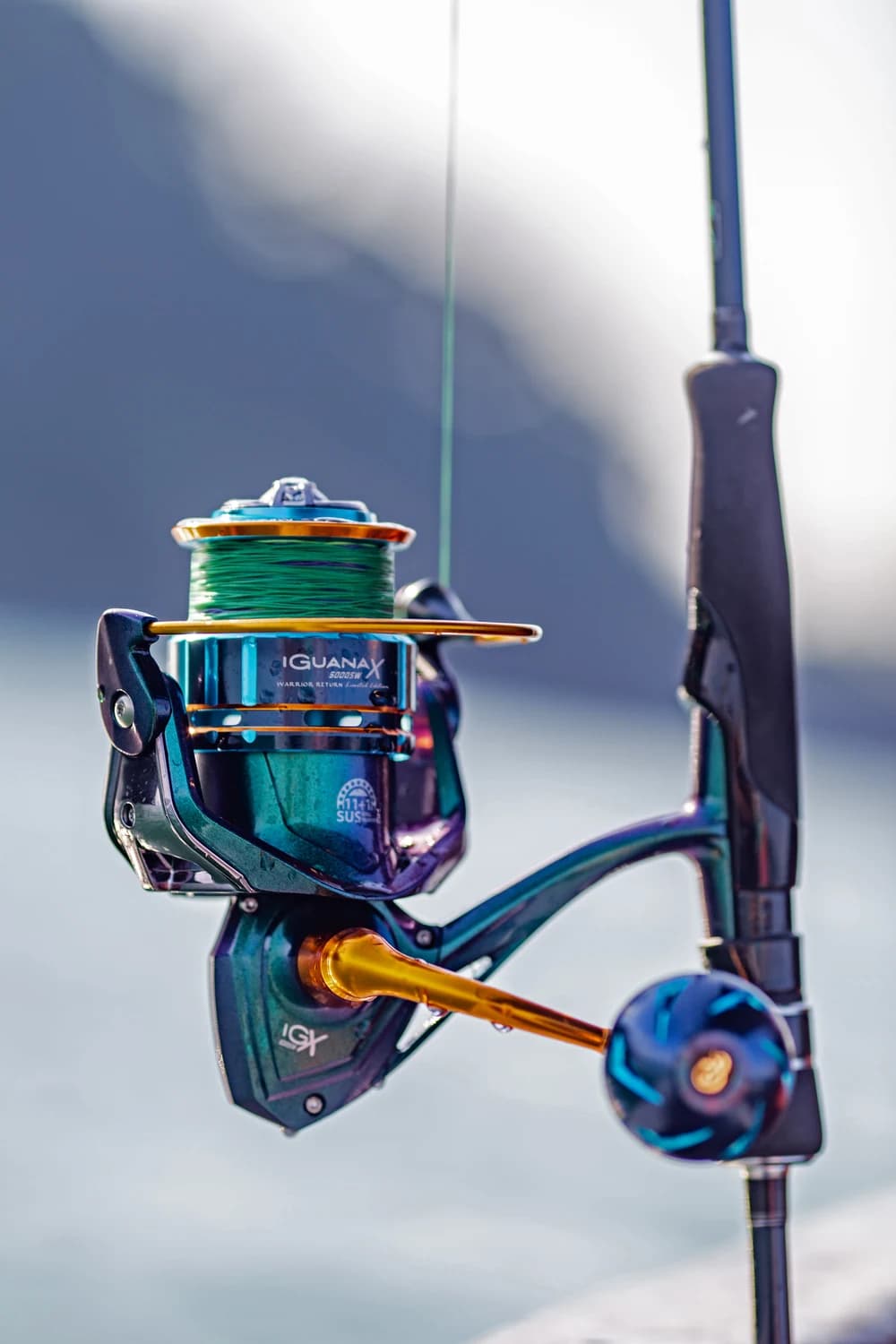 The iridescent blue and gold Iguana X fishing reel with green line.